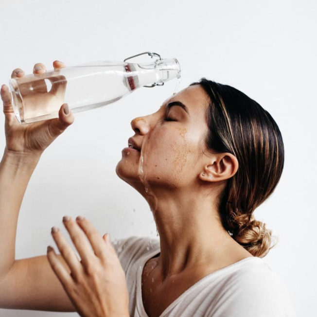 woman pouring water on her face