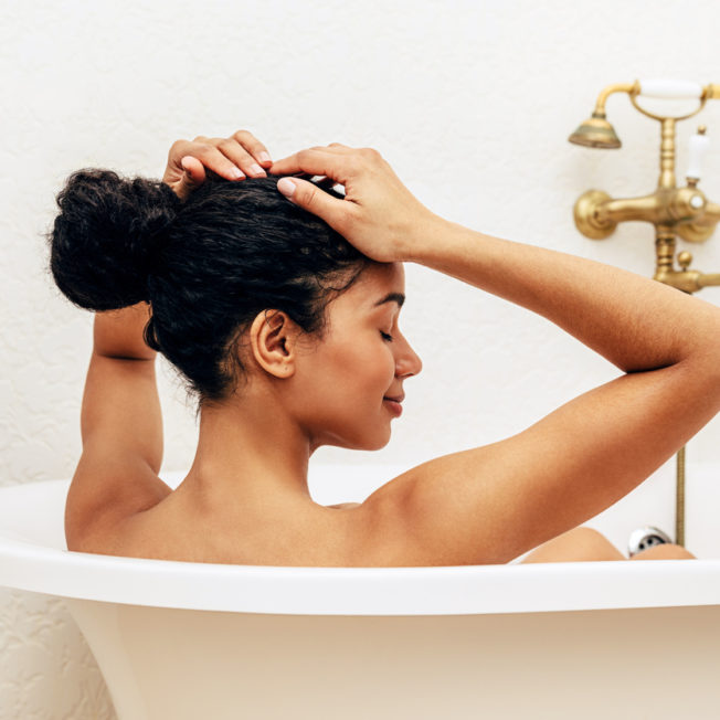 Woman relaxing in bathroom, straightens her hair
